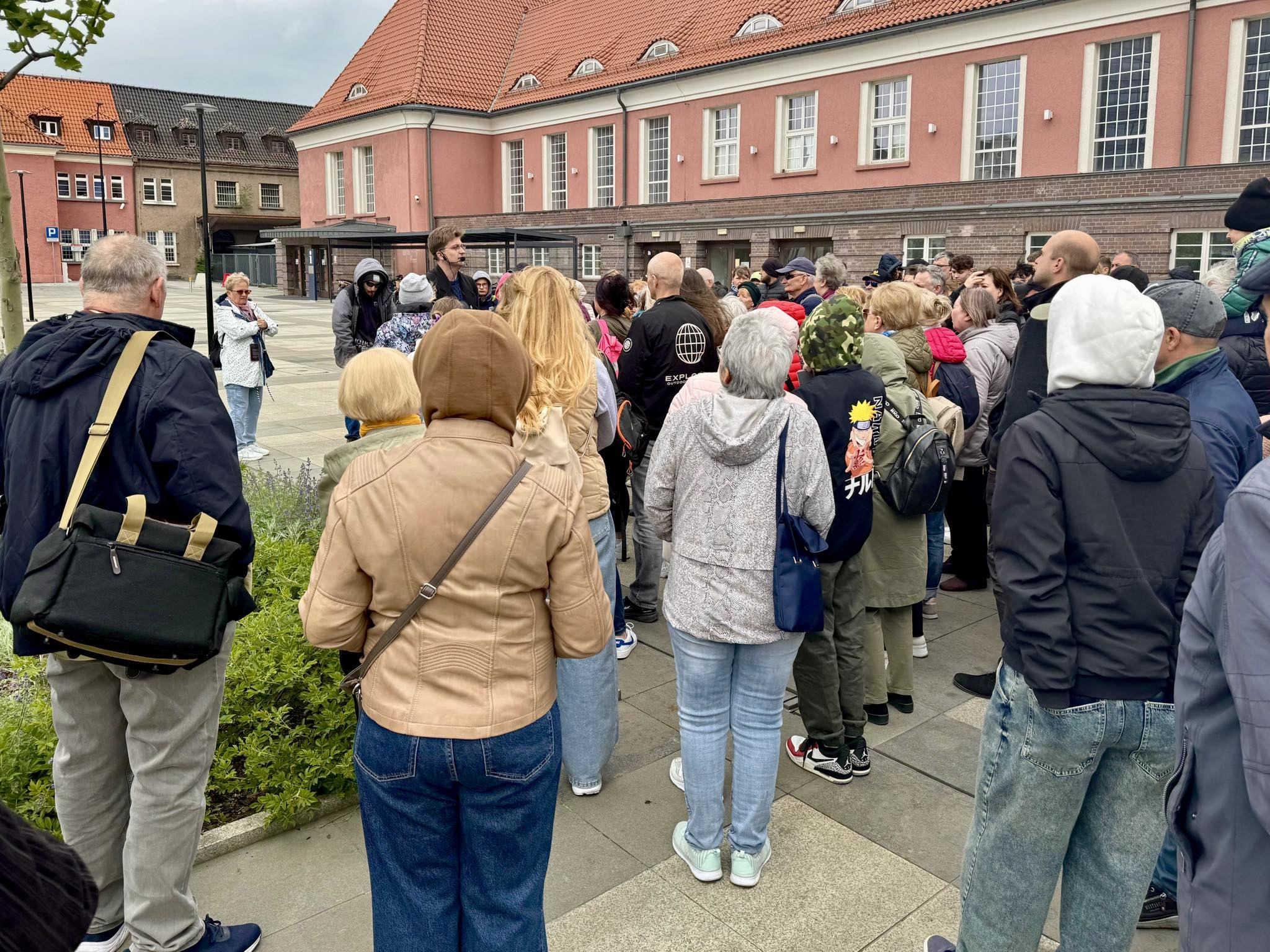 Grupa z przewonikiem przed budynkiem dworca