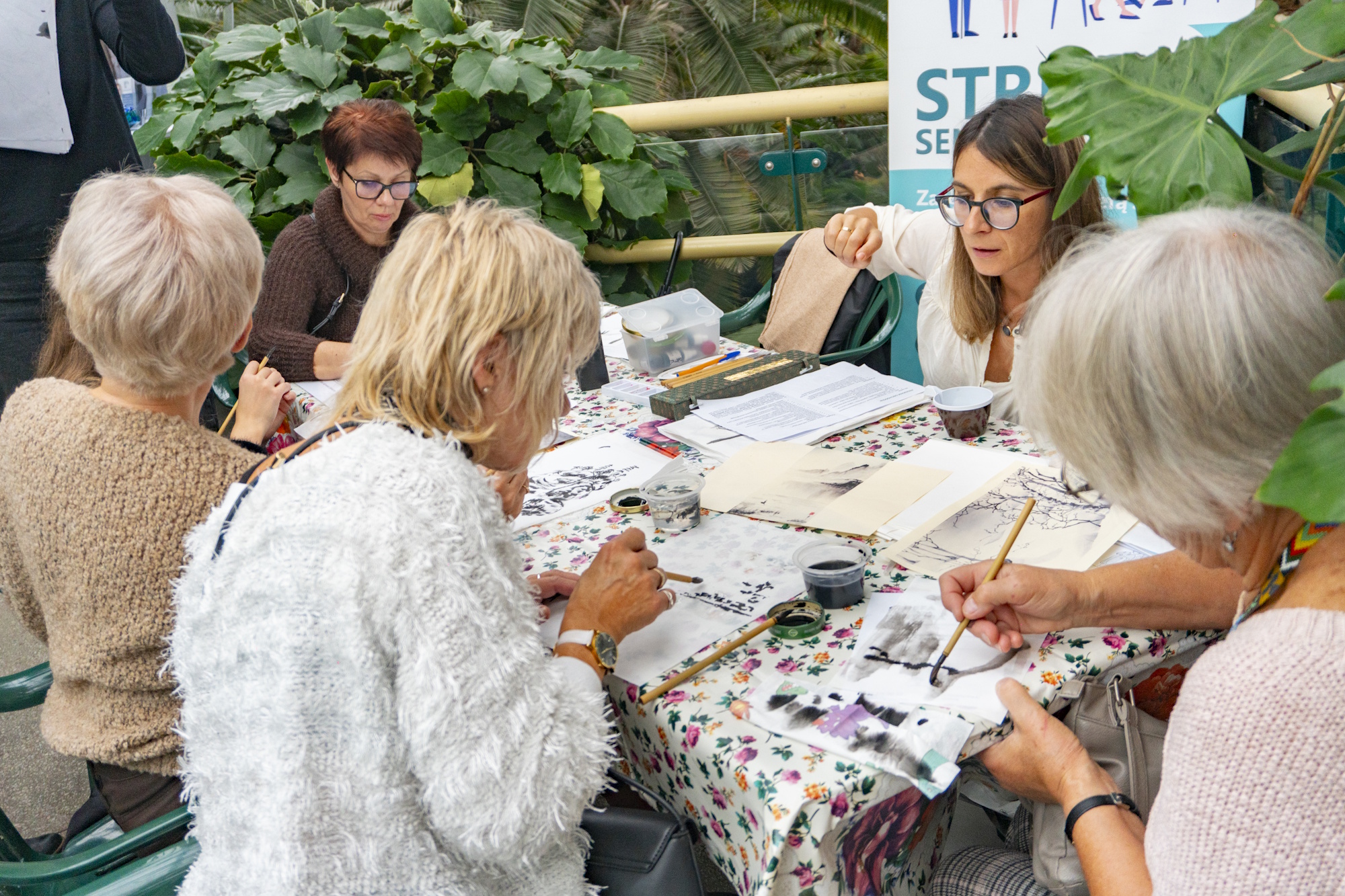 ludzie przy stole malują