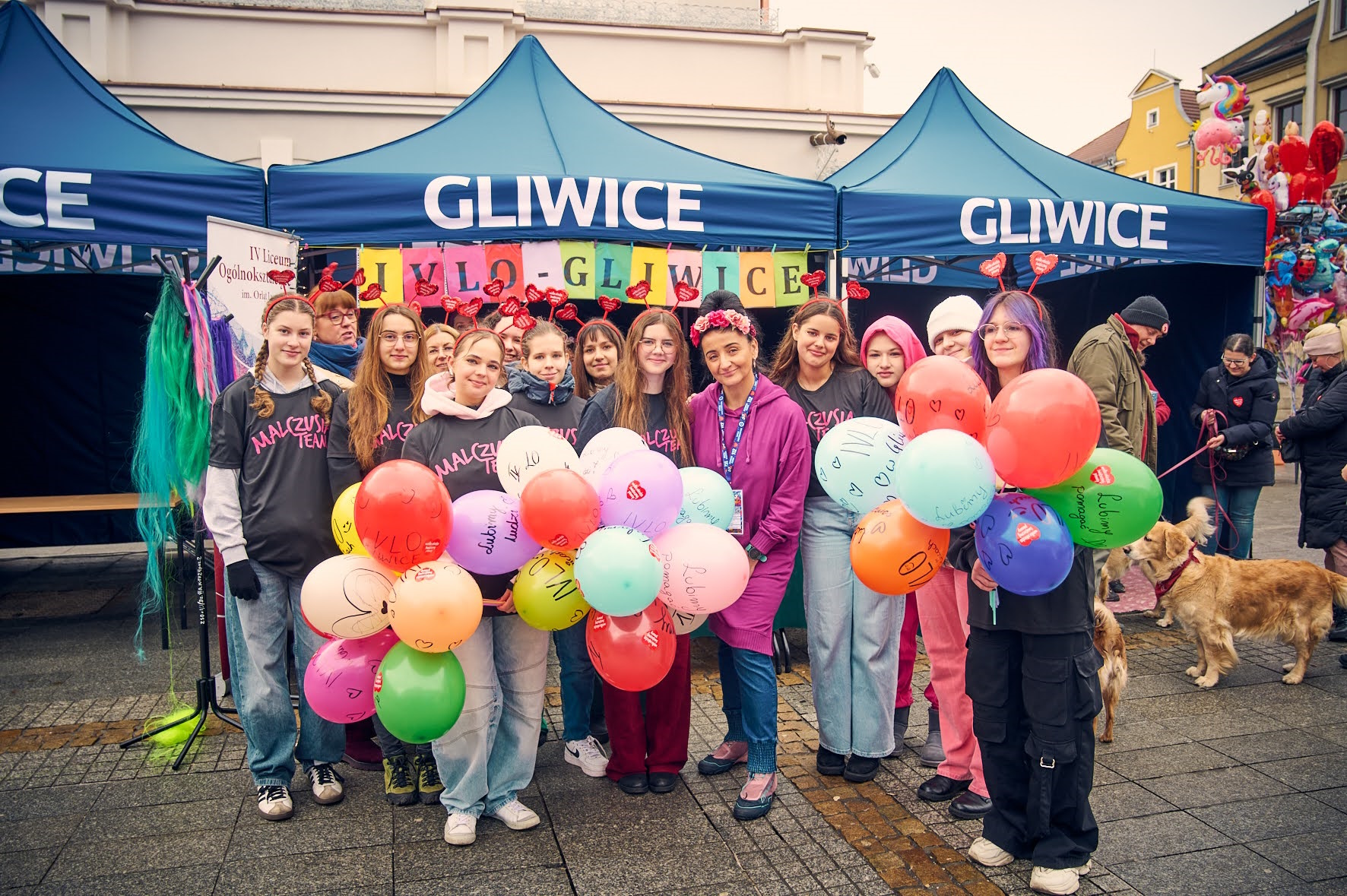 Fot. M. Buksa/UM w Gliwicach Uczniowie i nauczycielka z kolorowymi balonami przy stoisku z napisem Gliwice