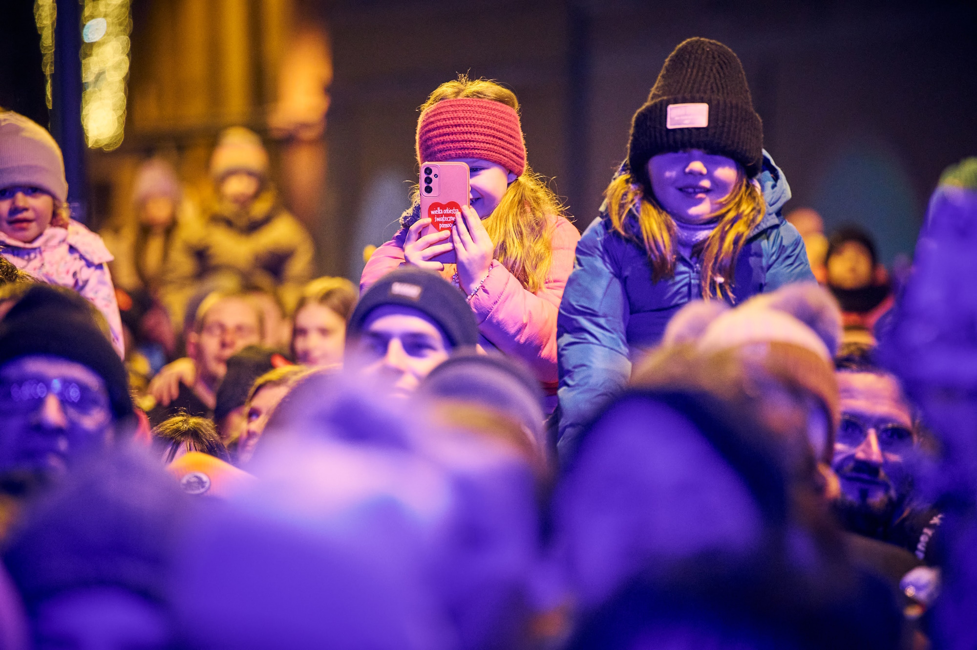 Fot. M. Buksa/UM w Gliwicach Dziewczynki na ramionach dorosłych ogladają koncert, jedna trzyma telefon, druga się uśmiecha