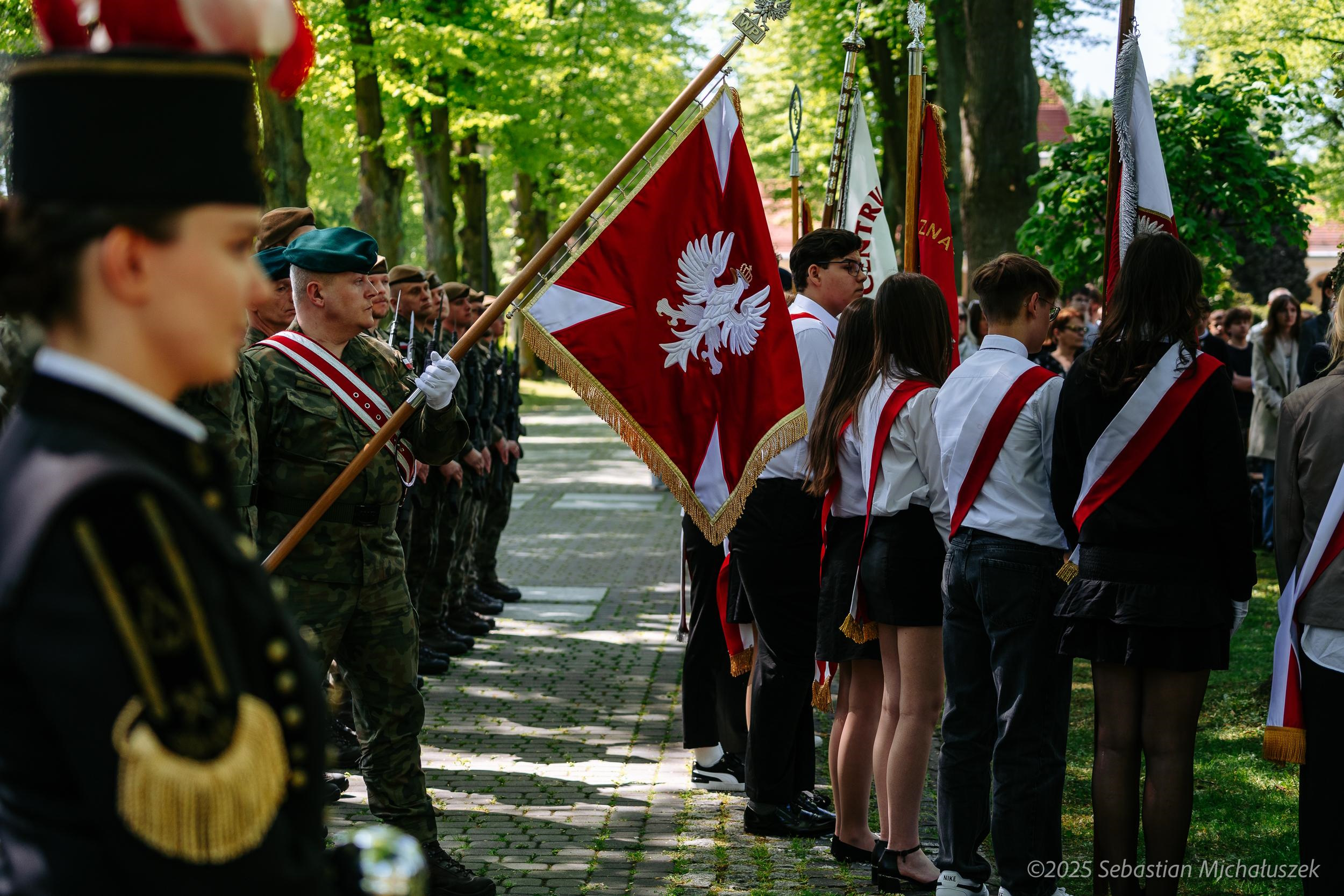 młodzi ludzie ze sztandarami na cmentarzu