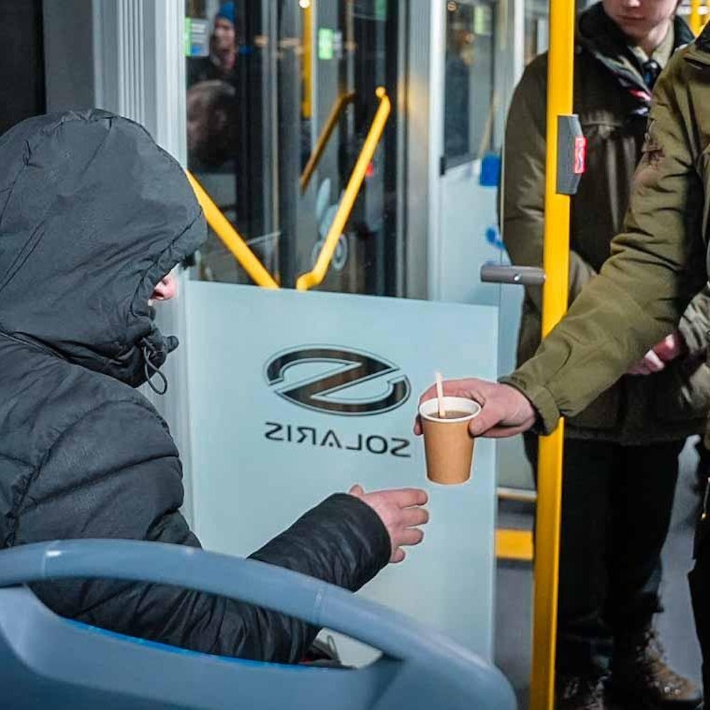 dwie ręce. Jedna podaje drugiej kubek z napojem