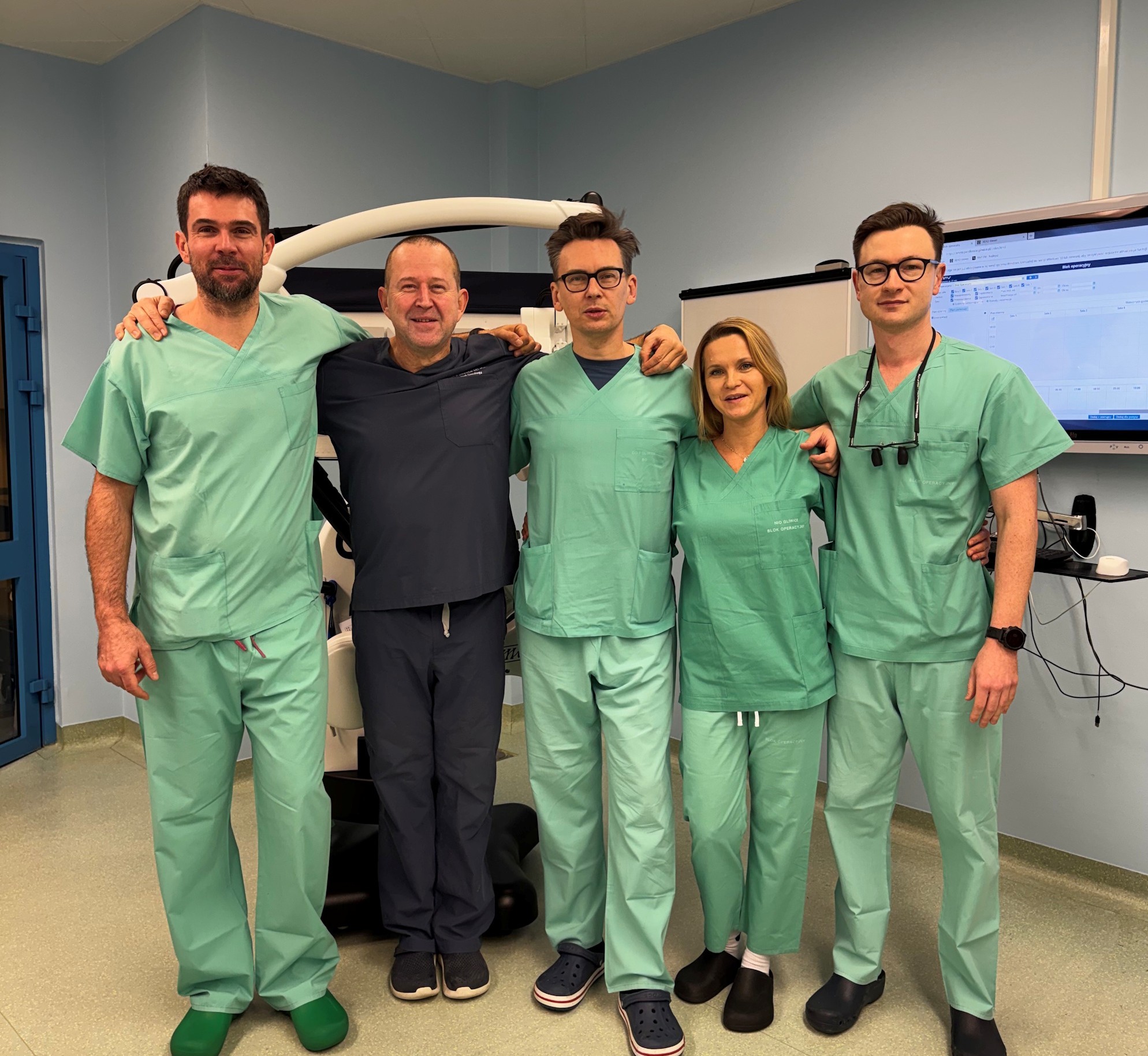 lekarze - czterech mężczyzn i kobieta, wszyscy w zielonej odzieży ochronnej 