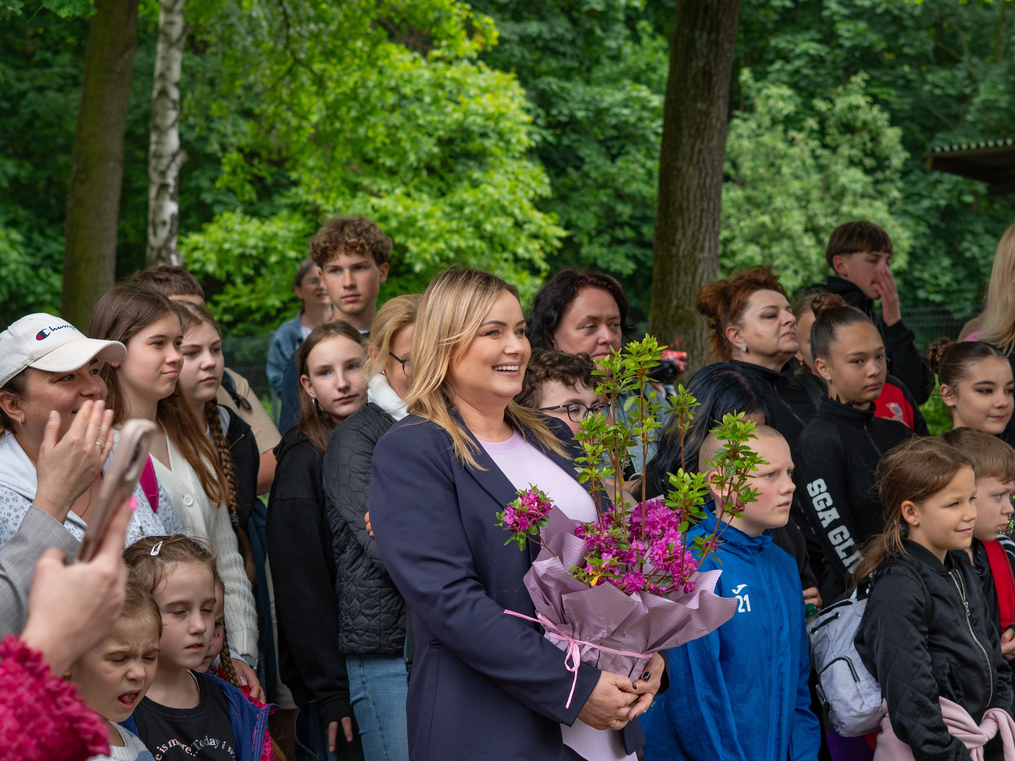 prezydent wśród dzieci z rośliną w rękach